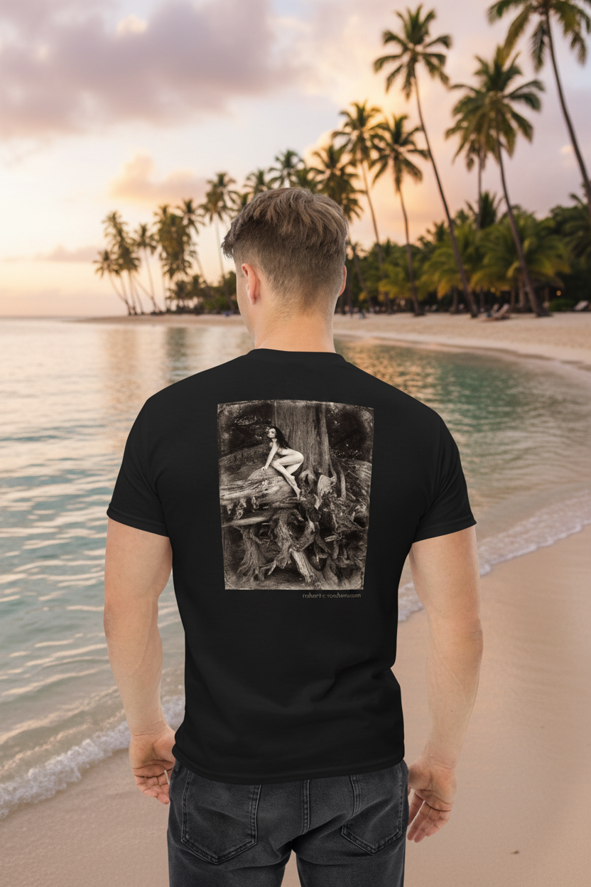 A man stands on a tropical beach facing away from the camera, wearing a black t-shirt with a large black-and-white graphic print on the back, paired with dark jeans. The background features a sandy beach, calm turquoise water, and a line of palm trees under a sunset sky.